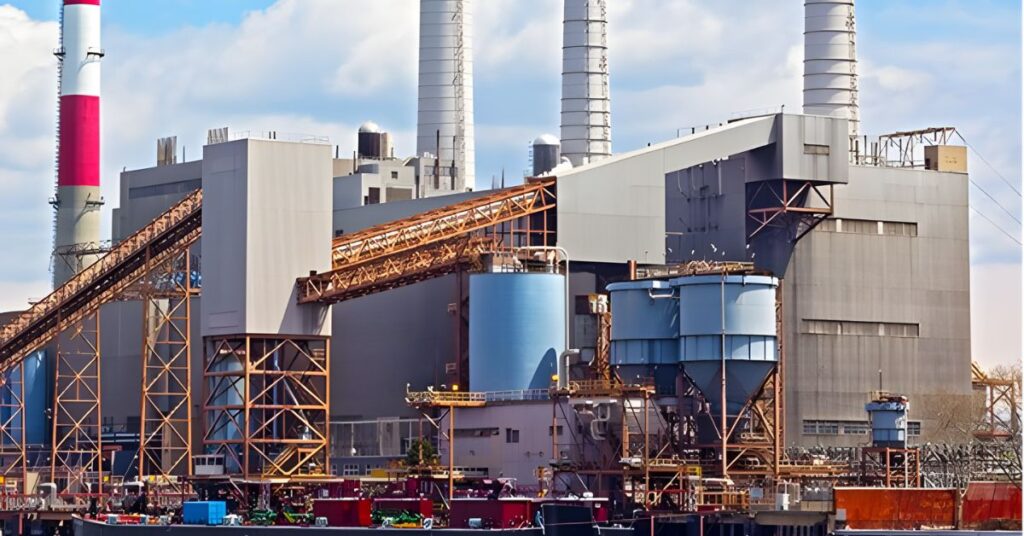 A power plant with four red and white smokestacks, surrounded by industrial buildings and equipment.