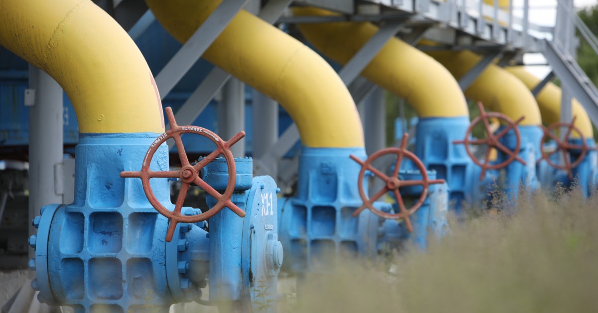 Several gas booster pumps are connected through a network of pipes. Each pump features a turning wheel attached to the side.