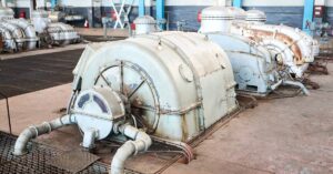 A nitrogen turbine compressor is surrounded by other industrial equipment in a room with wall-mounted ducts and floor grates.